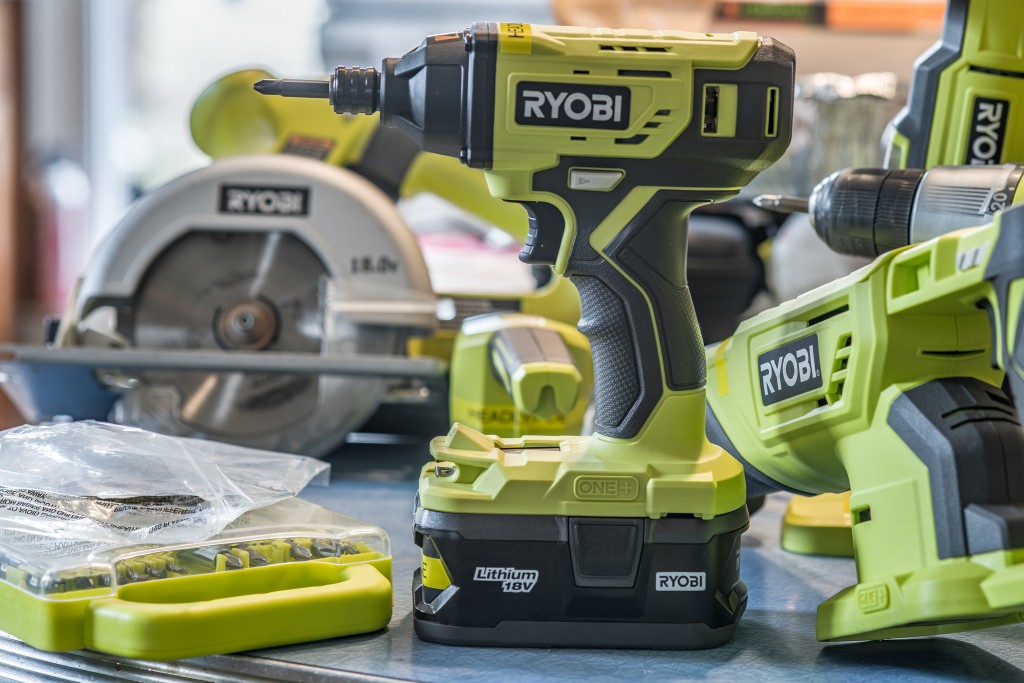 an assortment of Ryobi tools, including an impact driver, skill saw, drill, drill bits, a jigsaw, and more