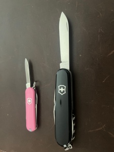 A Victorinox Spartan next to a Victorinox Classic SD; both have their knives extended